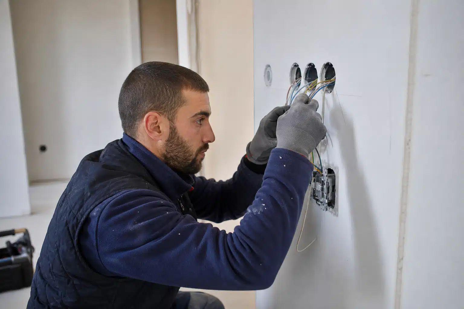 Électricien installant des prises murales avec gants